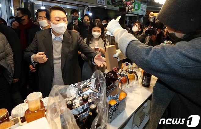 (강릉=뉴스1) 이동해 기자 = 윤석열 국민의힘 대선 후보가 10일 저녁 강원도 강릉시 중앙시장을 방문해 꿀을 구매하고 있다. 2021.12.10/뉴스1
