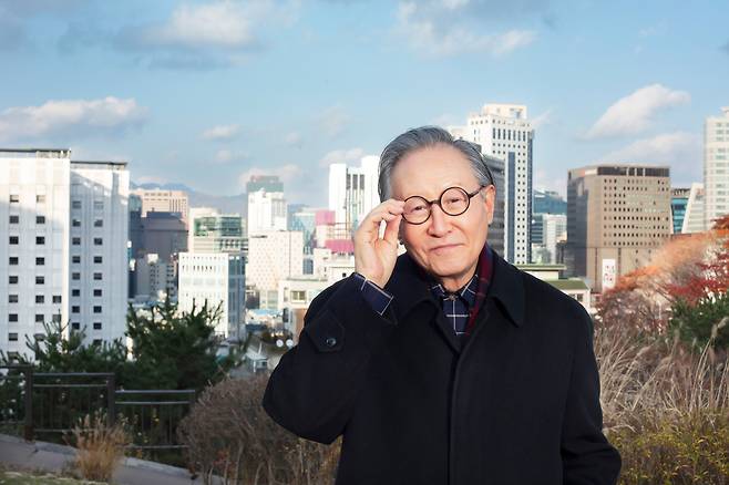 건축가 김종성이 서울 시내를 배경으로 서서, 트레이드 마크가 된 동그란 뿔테 안경을 매만졌다. 저멀리 왼쪽으로 그가 디자인한 서울 서린동 SK 사옥(빨간 마크가 있는 건물) 윗 부분이 보인다. /양수열 영상미디어 기자