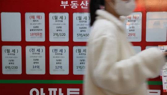 한 시민이 부동산 매물정보가 붙어 있는 공인중개업소 게시판 앞을 지나가고 있다.