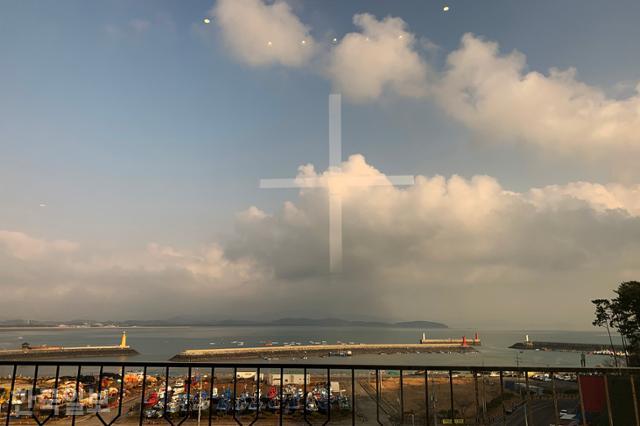 성경전래지기념관 예배당 유리창으로 보이는 마량포구 풍경. 유리창에 정면 십자가가 반사된 모습이 보인다.