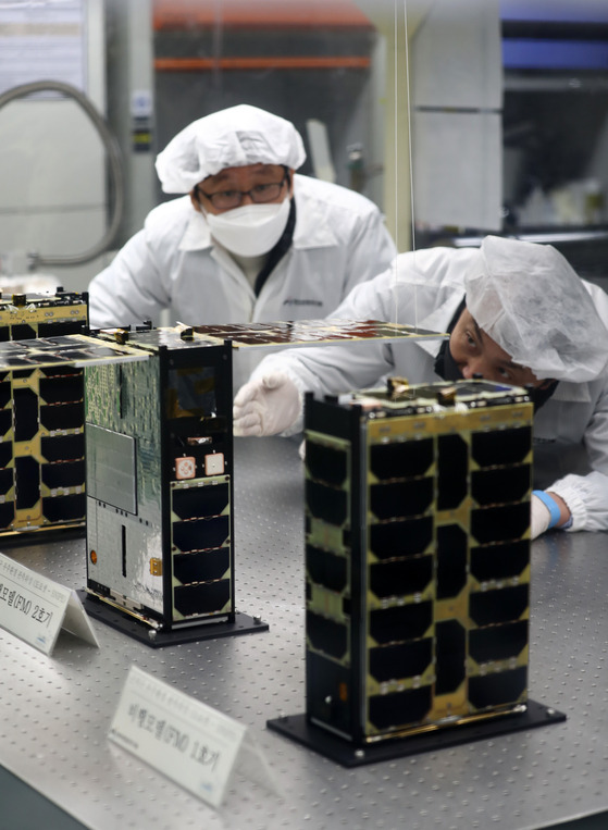 Researchers inspect the Snipe, a nanosatellite that will be used to monitor the weather, at the Korea Astronomy and Space Science Institute in Yuseong District, Daejeon, on Wednesday. The satellite, revealed Wednesday, will launch into space in the first half of next year at the Baikonur launch site in Kazakhstan on Russia's Soyuz-2 rocket. [YONHAP]