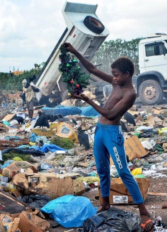 엄마와 함께 쓰레기장에 돈을 벌기 위해 찾아간 12살의 브라질 어린이가 버려진 크리스마스 트리를 진지하게 쳐다보고 있다. /사진=홍콩 SCMP