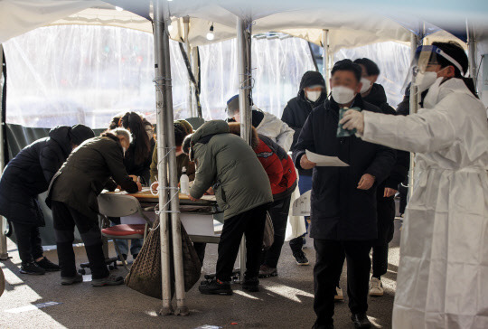 질병관리청에서 관리하는 코로나19 선별검사 시스템 접속에 문제가 생긴 18일 서울역 광장에 마련된 임시 선별검사소에서 시민들이 접수를 위해 수기로 관련 설문지를 작성하고 있다. 연합뉴스