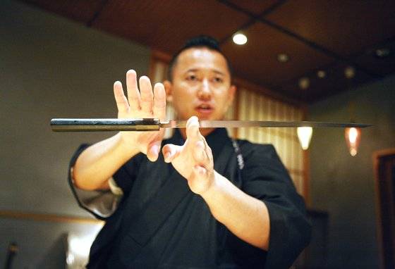 스시 교텐의 스시 장인 교텐 겐지. 칼을 들고 설명하고 있다.