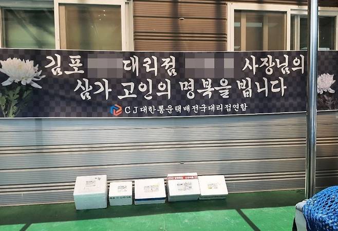 극단적 선택으로 숨진 김포 택배점주 추모 현수막 아래에 부피가 큰 택배 상자들이 줄지어 늘어선 사진. 지난 9월 택배업계에서 화제가 됐다. /연합뉴스