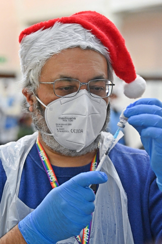 25일(현지시간) 영국 국민보건서비스(NHS)가 런던 동부 레드브리지에 마련한 임시 접종소에서 산타클로스 모자를 쓴 자원봉사자가 코로나19 백신 접종을 준비 중이다./AFP연합뉴스