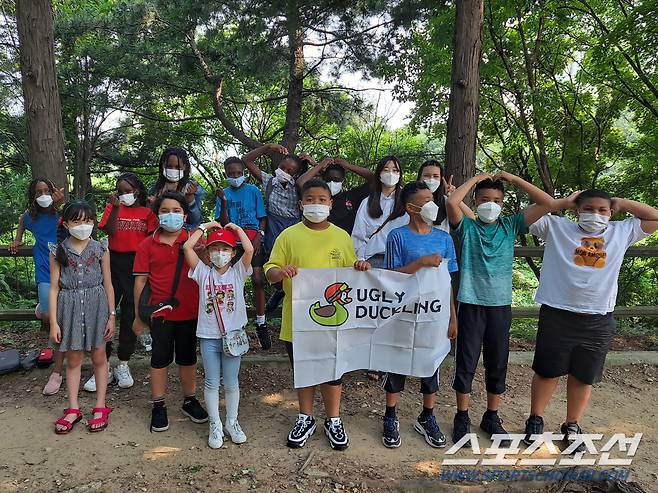 다문화가정 어린이농구단이 다문화가정에 희망을 전하는 '어글리덕클링 프로젝트 깃발을 들고 기념촬영을 하고 있다. 사진제공=한국농구발전연구소