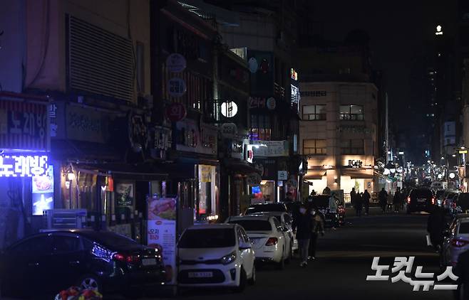 한국외식업중앙회 등 6개 소상공인 단체로 구성된 '코로나 피해 자영업 총연대'(코자총) 회원들이 지난해 12월 28일 서울 광진구 구의동 먹자골목에서 정부의 코로나19 방역 정책에 반발하며 간판에 불을 끄며 소등 시위를 벌이고 있다. 이한형 기자