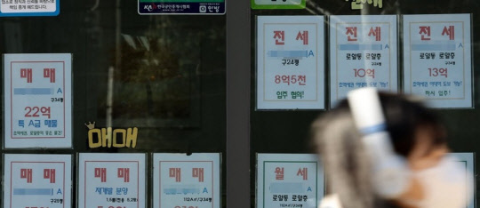 한 시민이 부동산 매물정보가 붙어 있는 공인중개업소 앞을 지나가고 있다. <연합뉴스>