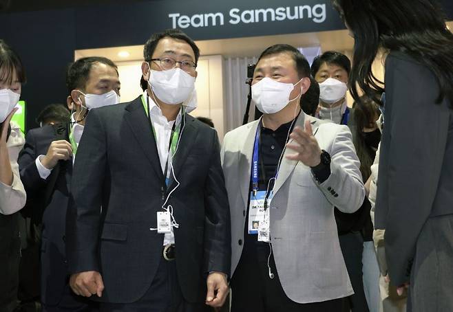 SK Telecom CEO Ryu Young-sang (left) and Samsung Electronics head of mobile experience division Roh Tae-moon talk at Samsung’s exhibition booth at CES 2022 in Las Vegas Wednesday. (SK Telecom)