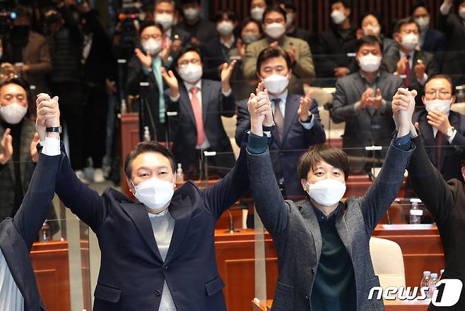 국민의힘 윤석열 대선 후보와 이준석 대표가 6일 오후 서울 여의도 국회에서 열린 의원총회에서 화해하며 잡은 손을 들어올리고 있다.2022.1.6/뉴스1 ⓒ News1 구윤성 기자