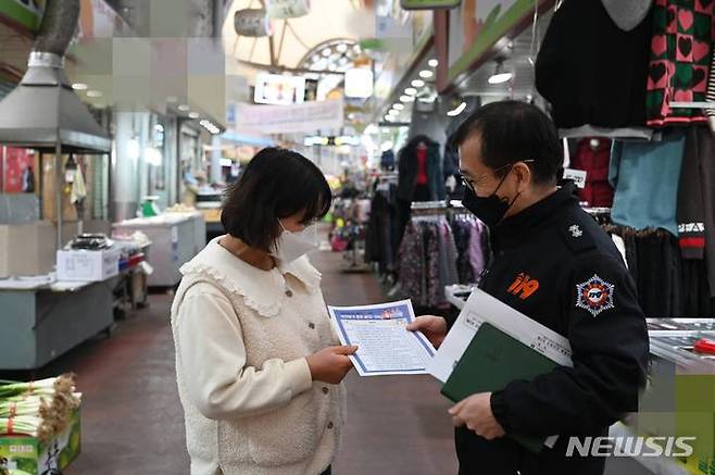 [대구=뉴시스] 이지연 기자 = 대구 서부소방서 특별조사팀장이 원고개시장의 한 상인에게 화재 안전을 위한 자율 점검 내용을 설명하고 있다. (사진=서부소방서 제공) 2022.01.10. photo@newsis.com