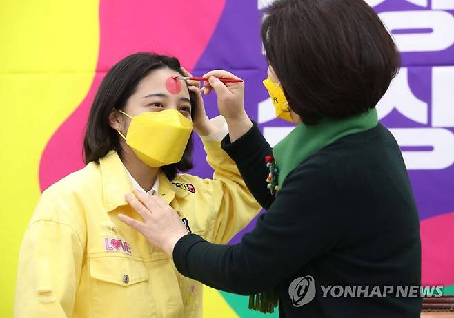 류호정 의원에게 페이스페인팅 해주는 심상정 후보 (서울=연합뉴스) 하사헌 기자 = 정의당 심상정 대선 후보가 17일 서울 여의도 국회에서 열린 정의당 PI 서브컬러 공개 브리핑에서 류호정 의원에게 새로운 PI와 서브컬러 모양의 페이스페인팅을 하고 있다. 2021.12.17 [국회사진기자단] toadboy@yna.co.kr