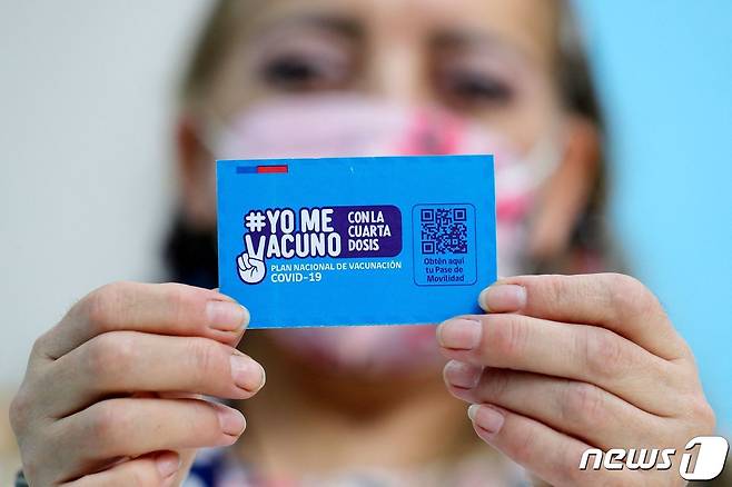 10일(현지시간) 칠레 산티아고 소재 모 신종 코로나바이러스 감염증 백신센터에서 한 여성이 '백신 카드'를 양손으로 들고 있다. 2022.01.10 © AFP=뉴스1