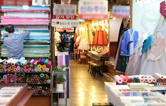 A store owner at a traditional market in Seoul on Tuesday displays colorful Korean traditional attire, hanbok, ahead of the Lunar New Year. Global interest in Korean attire has gone up, with Zara releasing a hanbok for kids in its Happy New Year’s Kids Collection. [YONHAP]