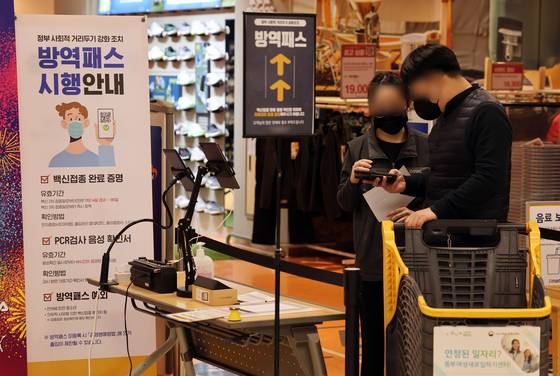 A shopper flashes a QR code to prove vaccination status upon entry to an Emart in Seoul on Wednesday. Under the strengthened vaccine pass policy, which went into effect Monday, large supermarkets and department stores require all customers to have vaccine passes for entry. [YONHAP]