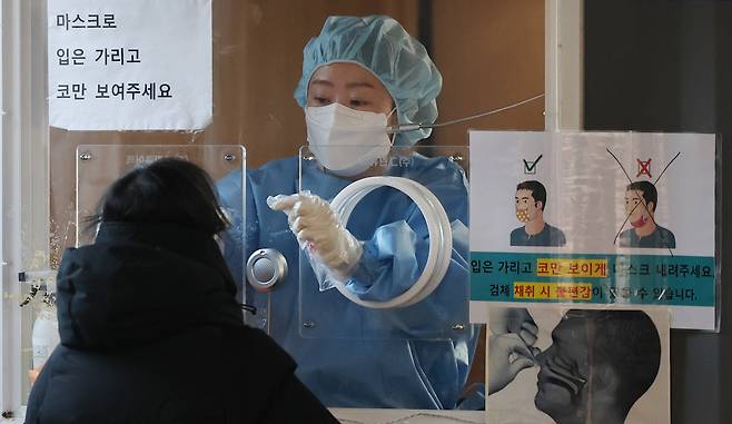 Health official takes a nasopharyngeal swab from a test seeker at a clinic set up outside Seoul Station on Friday. (Yonhap)