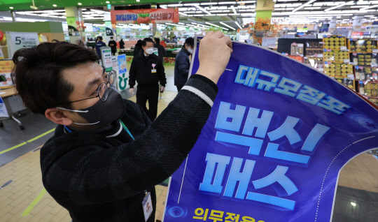 한 14일 오후 서울 서초구 양재동 농협하나로마트에서 관계자들이 방역패스 안내문을 치우고 있다. <연합뉴스>