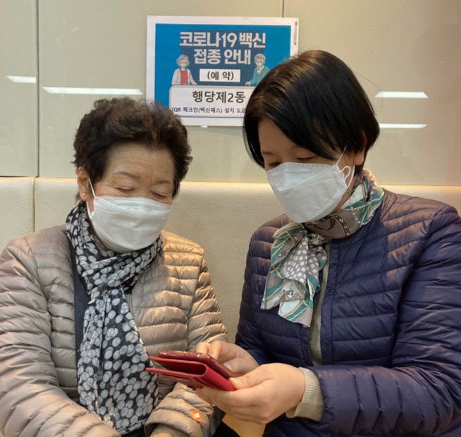 서울 성동구 행당제2동 주민센터 직원(오른쪽)이 동네 어르신에게 스마트폰을 통한 QR체크인 방법을 설명하고 있다. | 성동구 제공