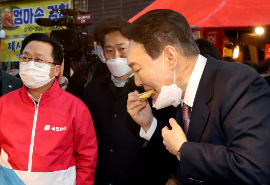 윤석열 국민의힘 대선 후보가 21일 오후 대전 동구 중앙시장을 찾아 전을 구매해 맛보고 있다.(사진=연합뉴스)