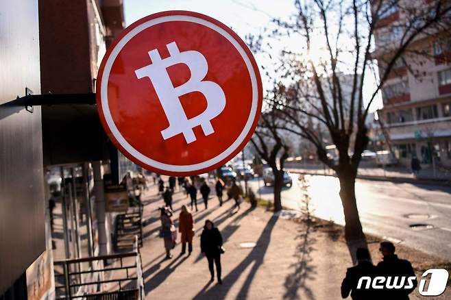 사람들이 2022년 1월 17일(현지시간) 코소보 프리스티나의 한 암호화폐 거래소에 전시된 비트코인 암호화폐 상징물 아래로 걸어가고 있다. © AFP=뉴스1 © News1 김지현 기자