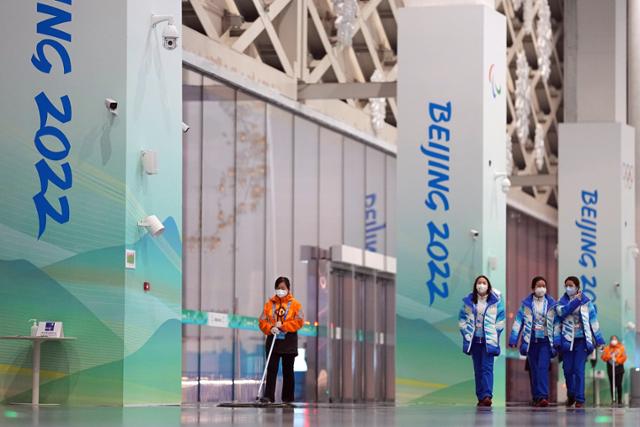 다음달 4일 개막하는 베이징동계올림픽을 앞두고 23일 조직위 관계자들이 베이징 미디어센터를 지나가고 있다. 베이징=AP 뉴스1