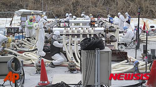 【도쿄=AP/뉴시스】동일본 대지진이 발생한지 오는 11일로 5년이 된다. 사진은 지난 2014년 3월 10일 후쿠시마(福島)현 오쿠마(大熊) 지역에 위치한 후쿠시마 제1원전에서 작업원들이 보호복을 입고 '동토차수벽'을 설치하고 있는 모습. 동토차수벽이란 방사성 물질에 오염된 지하수가 바다로 유입되는 것을 방지하기 위한 장치로, 원전 주변에 길이 약 1.4㎞의 동결관을 설치한 뒤 냉각제를 순환시켜 땅을 얼려, 지하수의 원전 유입을 차단하는 시설이다. 2016.03.08.