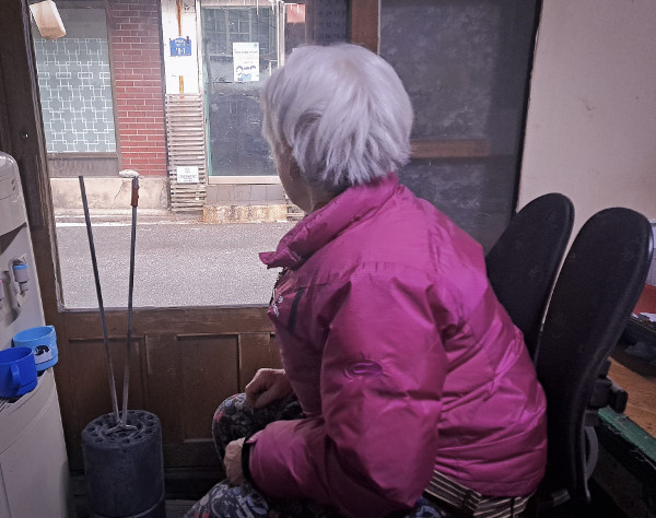 서울 노원구 중계본동 백사마을의 한 연탄 사용 가구 주민이 24일 창밖을 바라보고 있다. 연탄은행 제공