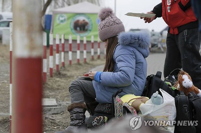 피란길 올라 길거리서 끼니 때우는 우크라 어린이 (메디카 AP=연합뉴스) 지난 4일(현지시간) 폴란드 국경도시 메디카로 피란 온 우크라이나의 한 소녀가 길거리에 앉아 끼니를 때우고 있다. 유엔난민기구(UNHCR)에 따르면 지난달 24일 우크라이나를 침공한 러시아군이 공세를 강화하면서 우크라이나 시민 100만여 명이 이웃 국가로 피신한 것으로 집계됐다. sungok@yna.co.kr