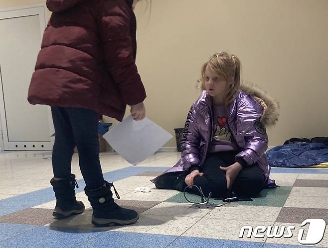 폴란드 프셰미실 인근 쇼핑센터에 마련된 피란민 임시 대피소에서 한 소녀가 7일(현지시간) 바닥에 설치된 콘센트를 활용해 꺼진 스마트폰을 충전하고 있다.© 뉴스1