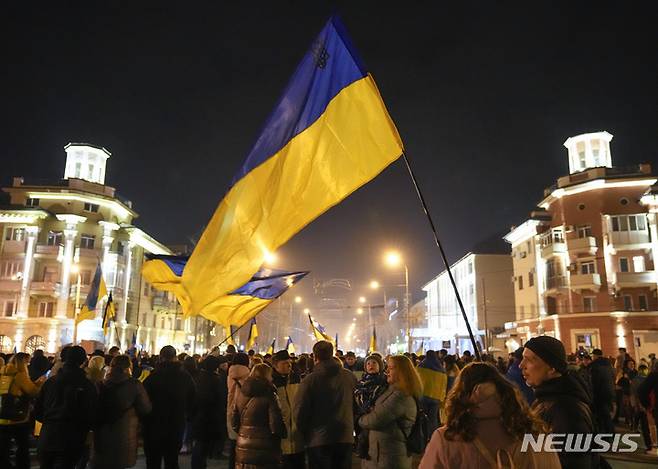 [마리우폴=AP/뉴시스] 22일(현지시간) 우크라이나 동부 도네츠크주 마리우폴에서 우크라이나인들이 국기를 들고 "마리우폴은 우크라이나 영토" 집회에 참석하고 있다. 러시아 상원은 블라디미르 푸틴 대통령의 러시아 영토 밖 군대 주둔 요청을 참석 의원 153명 만장일치로 승인했다. 2022.02.23.