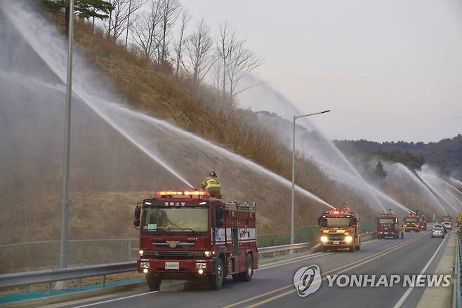 '불길을 막아라' (울진=연합뉴스) 울진·삼척산불 발생 닷새째인 8일 오후 6시께 경북 울진군 울진읍 대흥리 금산터널에서 소방차들이 산불 방어선 구축을 위한 일제 방수를 하고 있다. 2022.3.8 [경북소방본부 제공. 재판매 및 DB 금지] mtkht@yna.co.kr