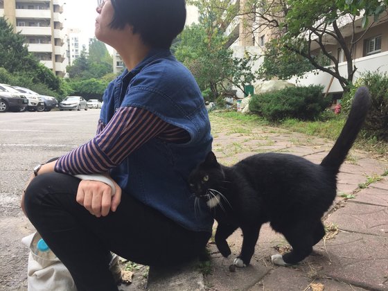 다큐멘터리 '고양이들의 아파트' 촬영 도중 쉬고 있는 정재은 감독에게 둔촌주공 아파트의 고양이가 다가와 친밀감을 표하고 있다. [사진 엣나인필름, 메타플레이]