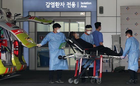 20일 중랑구 서울의료원에서 의료진이 코로나19 환자를 옮기고 있다.   연합뉴스