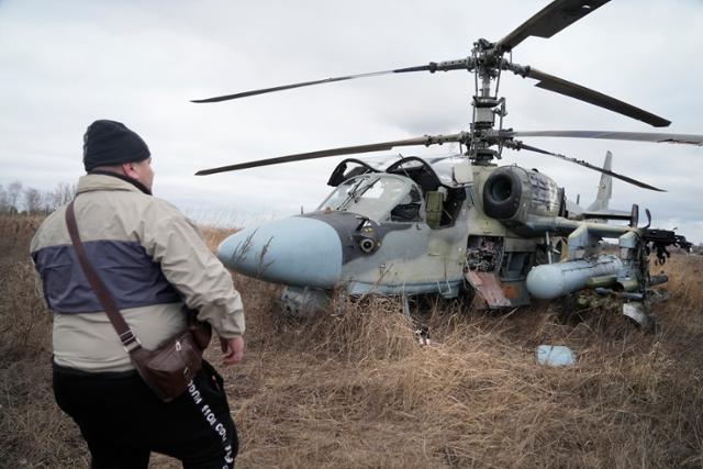 러시아가 우크라이나를 침공한 지난달 24일 키이우 외곽에서 한 주민이 격추된 러시아군의 헬기를 살펴보고 있다. 키이우=AP 연합뉴스