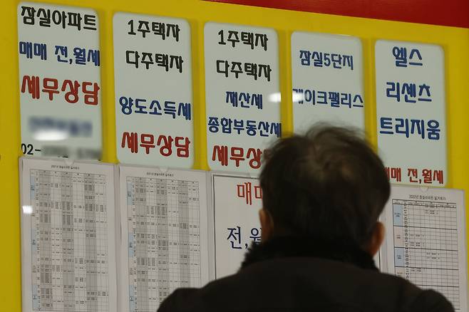 서울 시내 한 부동산 중개업소 게시판을 지나가던 시민이 바라보고 있다. [연합]