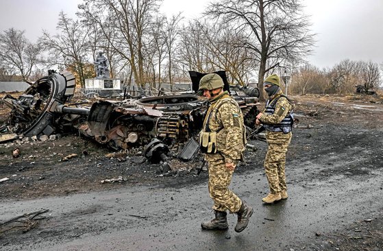 우크라이나 군인들이 수도 키이브 인근 루키아니프카 마을에서 파괴된 러시아 탱크 옆을 지나가고 있다. AFP=연합뉴스