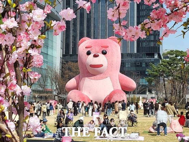 봄꽃 나들이를 나온 시민들이 4일 오후 서울 송파구 롯데월드타워 잔디광장에 전시된 대형 곰인형 '벨리곰'을 감상하고 있다. /김미루 인턴기자