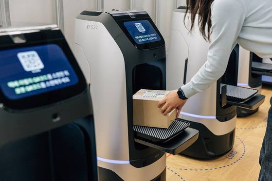 An employee puts a package in a delivery robot Rookie. [NAVER]