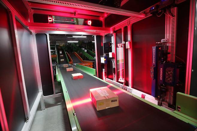 20일 밤 충북 진천군 롯데글로벌로지스 진천 메가 허브터미널에서 공항 보안검색대를 닮은 인공지능(AI) 분류 설비가 컨베이어벨트 위의 택배들을 스캔해 크기별로 분류하고 있다. 이 설비에 탑재된 AI 이미지 인식 시스템은 롯데글로벌로지스 다른 물류센터에서 3년간 택배 이미지들을 학습한 덕분에 분류 정확도가 99%에 이른다. /신현종 기자