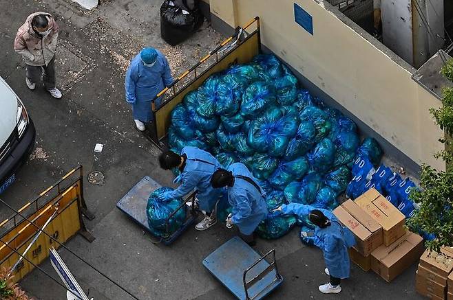 [사진: AFP-연합] 외출이 금지된 격리 주민들에게 배급할 채소를 나눠담는 방역요원들. 지난 4월16일 상하이 징안 구.