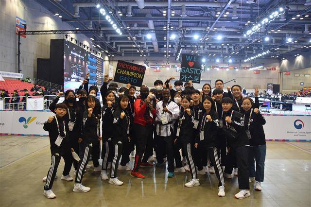 지난 23일 경기 고양시 킨텍스에서 열린 ‘2022 고양 세계태권도품새선수권대회’에서 공인 품새 시연을 마친 가스토 은사주무키자(앞줄 오른쪽 다섯 번째)와 한국대표팀 선수들이 기념사진을 찍고 있다.유엔난민기구 한국대표부 제공