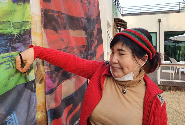 장혜숙 화가가 지난 3월 경남 양산 통도사 성보박물관에 열린 전시회 안내문을 천에 그리고 있다.