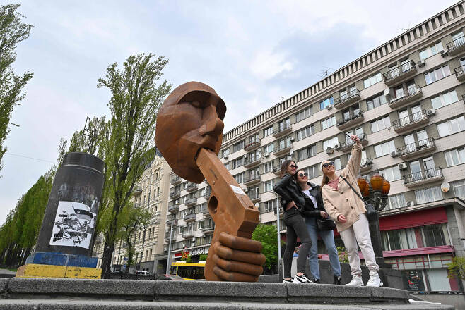 우크라이나 수도 키이우 중심가에 7일(현지시간) 설치된 푸틴 대통령 조형물 앞에서 일부 시민이 기념 사진을 찍고 있다.