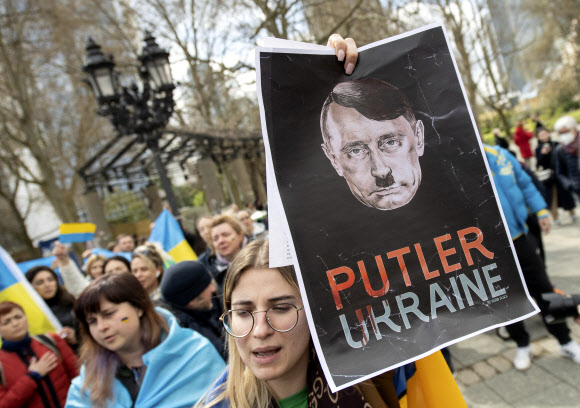 독일인의 ‘맞물’ 시위 - 10일(현지시간) 독일 프랑크푸르트에서 열린 친러시아 시위에 대해 독일인들이 블라디미르 푸틴 러시아 대통령을 아돌프 히틀러와 합성한 이미지를 들어보이며 러시아의 우크라이나 침공을 비판하는 ‘맞불 시위’를 벌이고 있다.프랑크푸르트 AP-DPA 연합뉴스