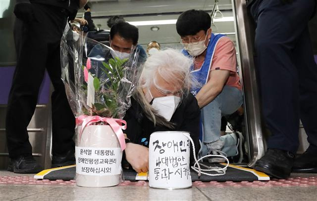 전장연, 취임 축하 화분 들고 오체투지 - 박경석 전국장애인차별철폐연대 공동대표가 10일 오전 서울 지하철 5호선 여의도역에서 윤석열 대통령 취임식날에 맞춰 ‘장애인 권리 예산 보장’ 등을 촉구하며 ‘오체투지’ 시위를 하고 있다. 이날 박 대표는 열차 안에서 ‘장애인 평생교육법 제정하라’ 등 문구가 적힌 장미꽃 화분과 깡통을 들고 바닥을 온몸으로 기며 출근길 시민을 상대로 장애인 권리 보장을 호소했다. 2022.05.10 뉴스1