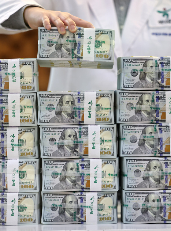 An employee holds a stack of dollar bills at Hana Bank's Counterfeit Notes Response Center in Jung District, central Seoul, on Wednesday. The local currency reached the 1,277-won-per-dollar level during the day, hitting this year's highest point, before closing at 1,275.30 won against the dollar, down 1.1 won from Tuesday's close. [YONHAP]