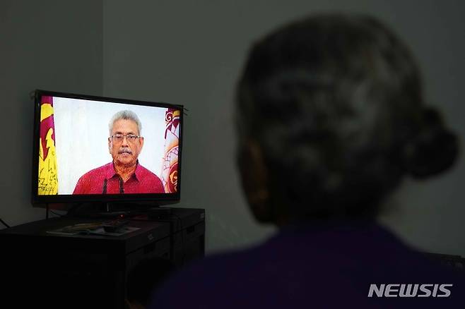 [AP/뉴시스] 11일 스리랑카 수도 콜롬보에서 통금령이 내려진 속에 주민이 텔레비전의 대통령 연설을 듣고 있다.