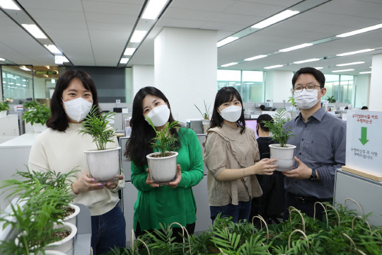 최근 열린 비대면 봉사활동 '공기정화 식물 기부'에 참여한 LG이노텍 직원들이 화분을 들고 기념사진을 촬영하고 있다. <LG이노텍 제공>
