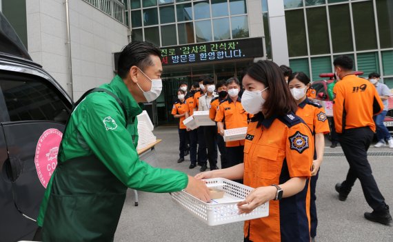 하이트진로 김인규 대표(왼쪽)가 지난 13일 강릉소방서 소방관들에 간식과 선물을 전달하고 있다.